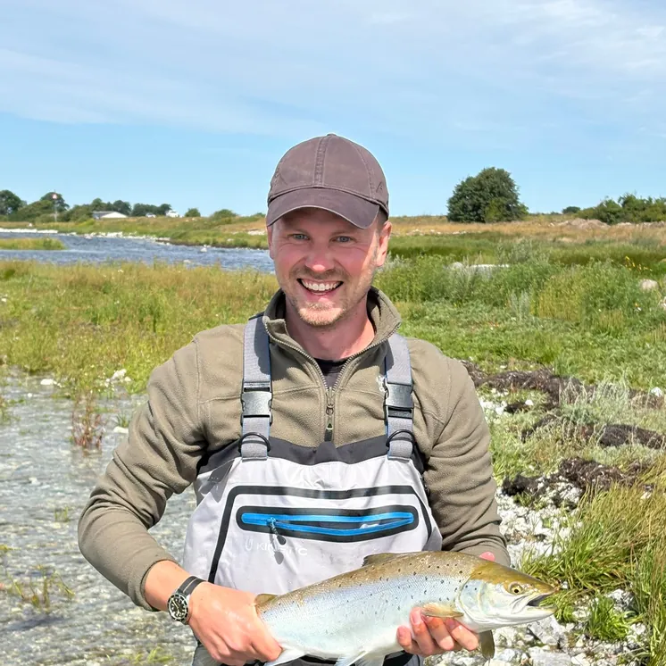 Lukas K. smiling with a sea trout after a guided trip in Sweden